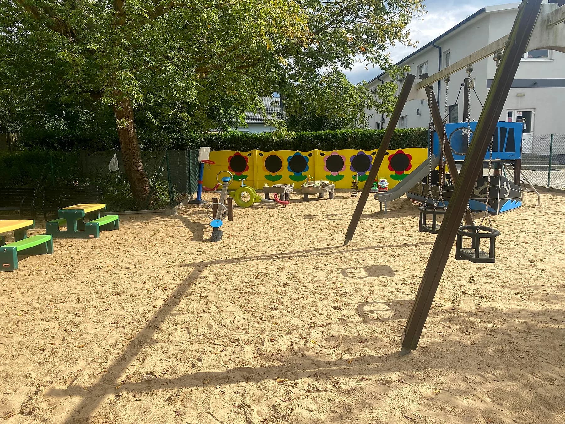 Huśtawki i ściana ze słonecznikami na placu zabaw